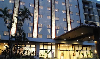A hotel with multiple floors, large windows, and a well-lit entrance.