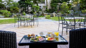 A patio with outdoor seating and a breakfast table set with food and drinks. - Community & Spa Naha Central Hotel (Naha)