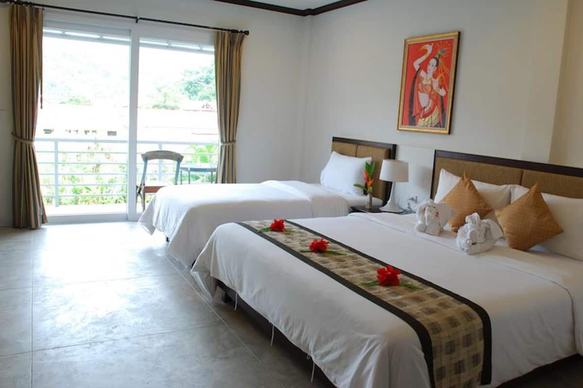 A hotel room with two beds, a window with curtains, a chair, and a painting on the wall.