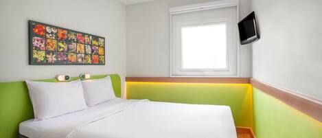 Una cama bien hecha con sábanas blancas, un cabecero verde y una obra de arte floral de colores en la pared.