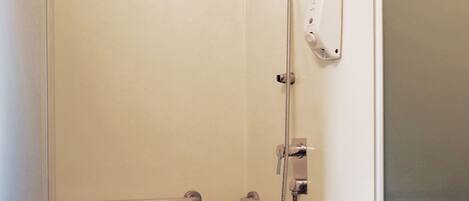 A bathroom with a shower, grab bars, and a sink.