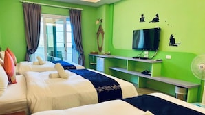 A hotel room with three beds, a TV, a mirror, and a fan.
