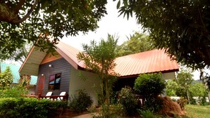 A small house with a red roof, surrounded by greenery and a pathway leading to a wooden deck with chairs. - Mild Garden View Resort (Krabi)