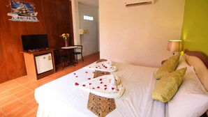 A hotel room with a bed, a desk, a television, and an air conditioning unit. - Mild Garden View Resort (Krabi)