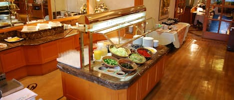 Un área de bufé con diversos alimentos y una vitrina de vidrio.
