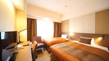 A hotel room with two beds, a desk with a computer, a chair, and a lamp.