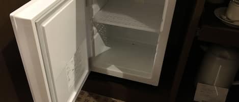 A white refrigerator with a freezer compartment, located in a kitchen with patterned flooring.