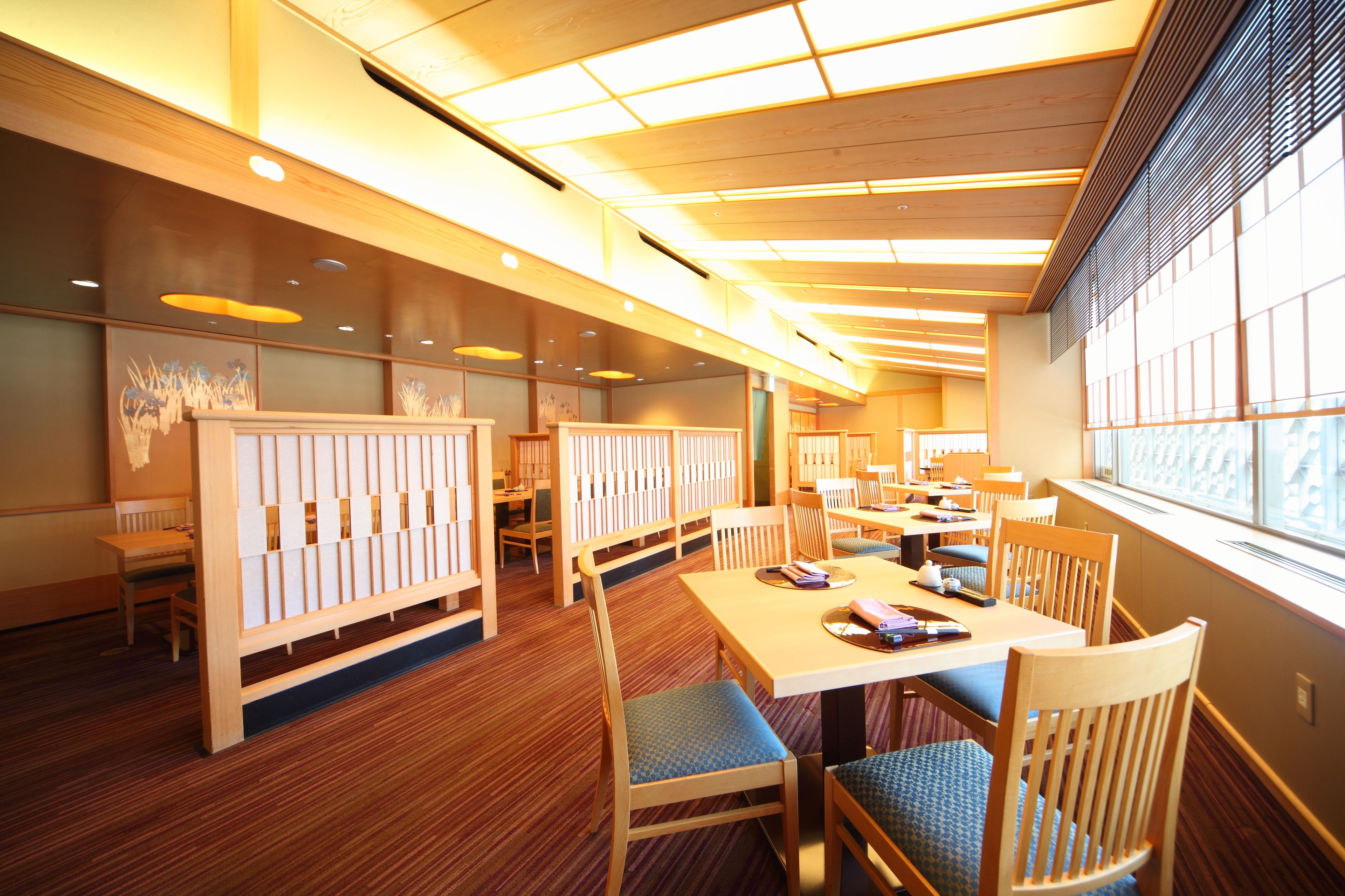 Un restaurante con muebles de madera, techo alto y ventanas amplias.