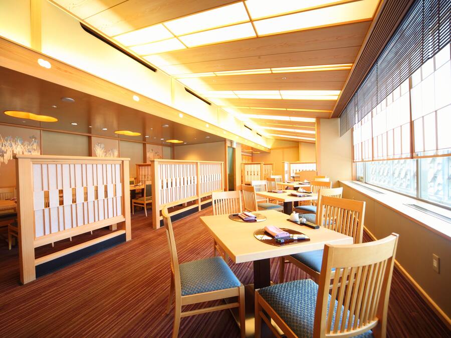 A restaurant with wooden furniture, a high ceiling, and large windows.