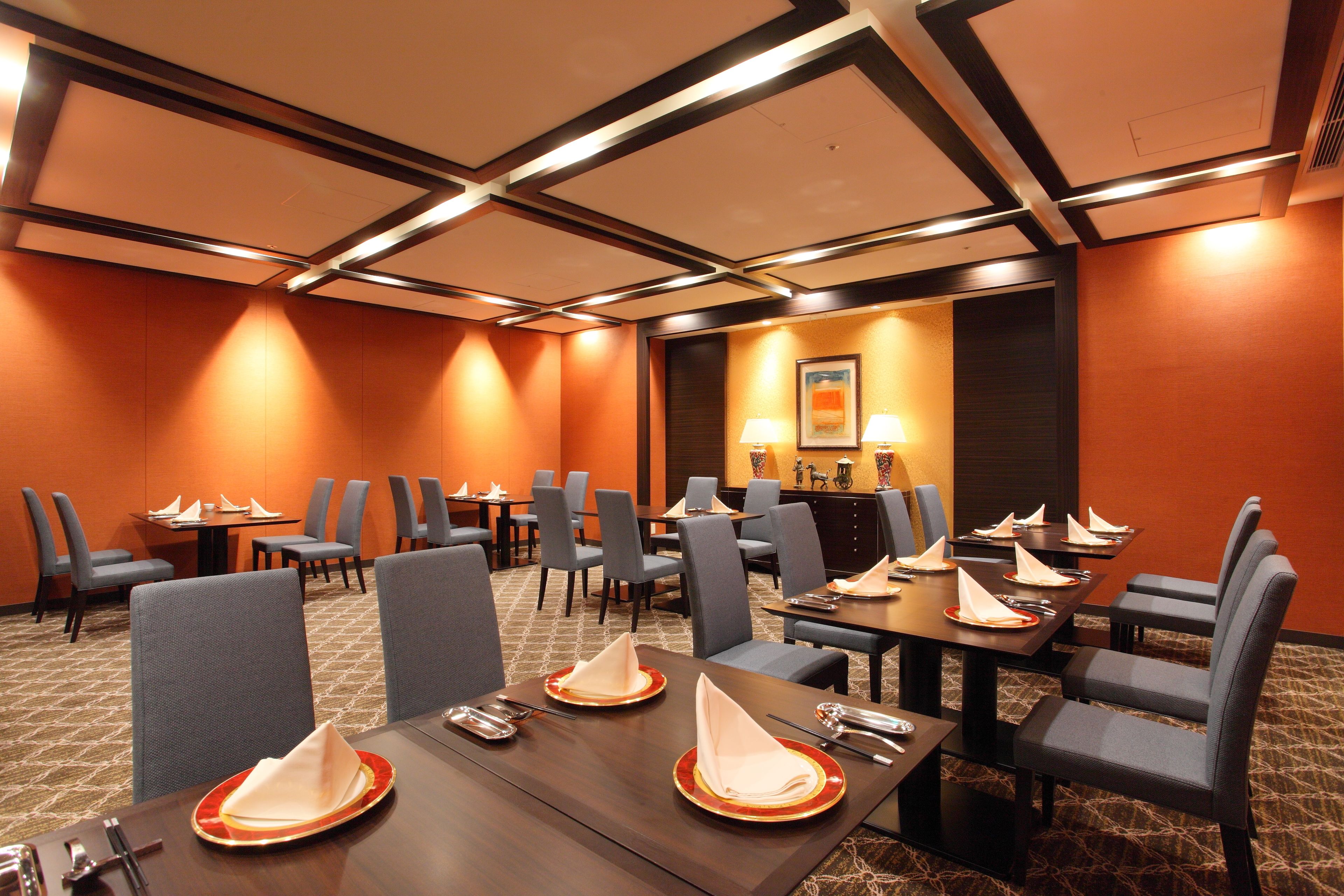 A conference room with tables set for a meeting, equipped with chairs and a projector screen.