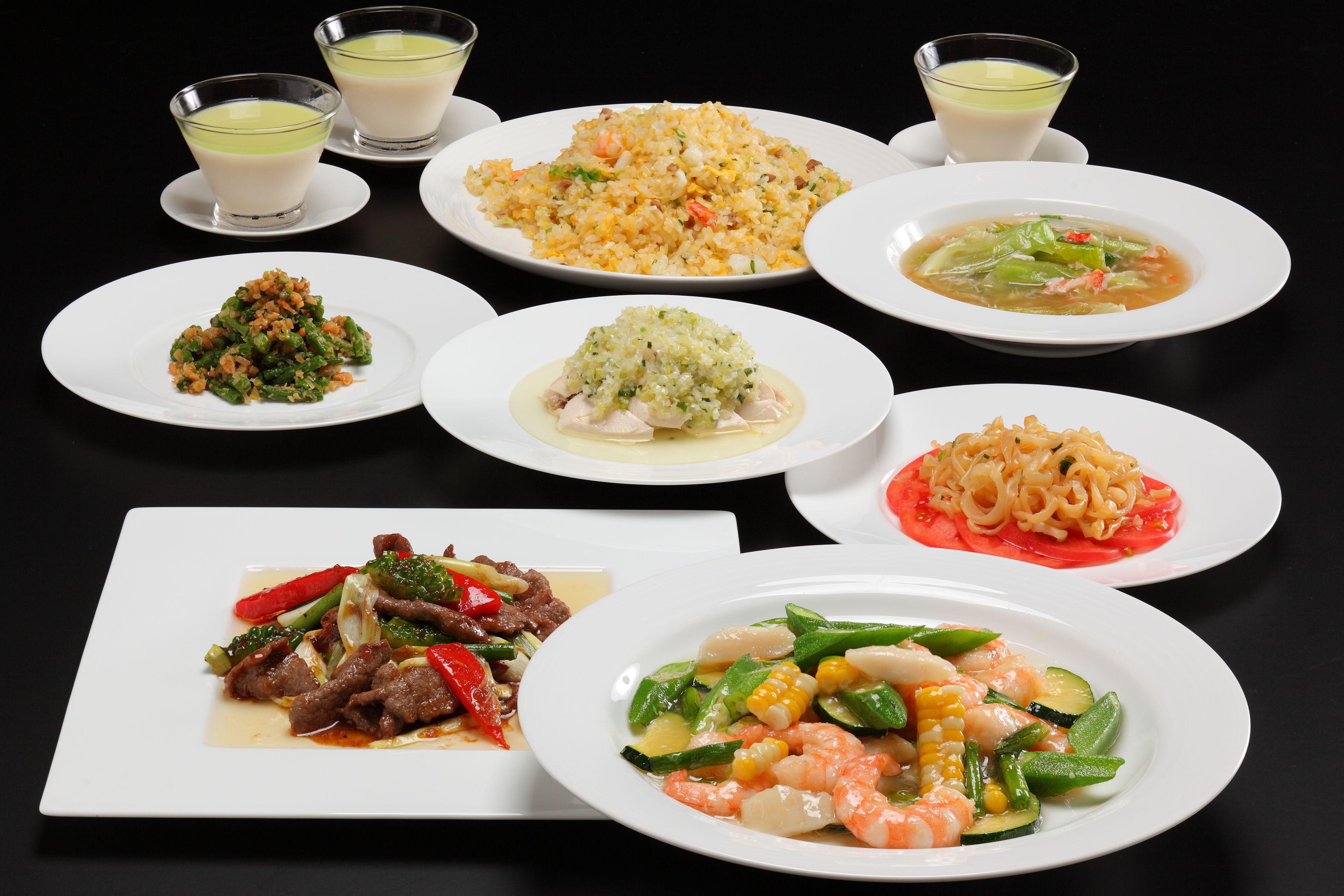 Une variété de plats, notamment du riz frit, une soupe et un plat de fruits de mer, présentés sur des assiettes.