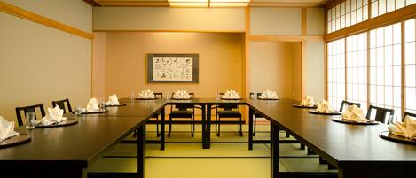 A conference room with a long table, chairs, and a framed artwork on the wall.