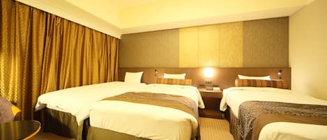 A hotel room with three beds, a small table, and a chair.