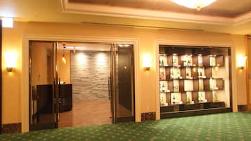 Um saguão de hotel com carpete verde, um display de vinhos e uma parede de pedra.