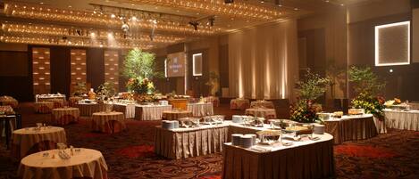 A banquet hall with round tables, floral centerpieces, and a projection screen displaying "Hotel Reception".