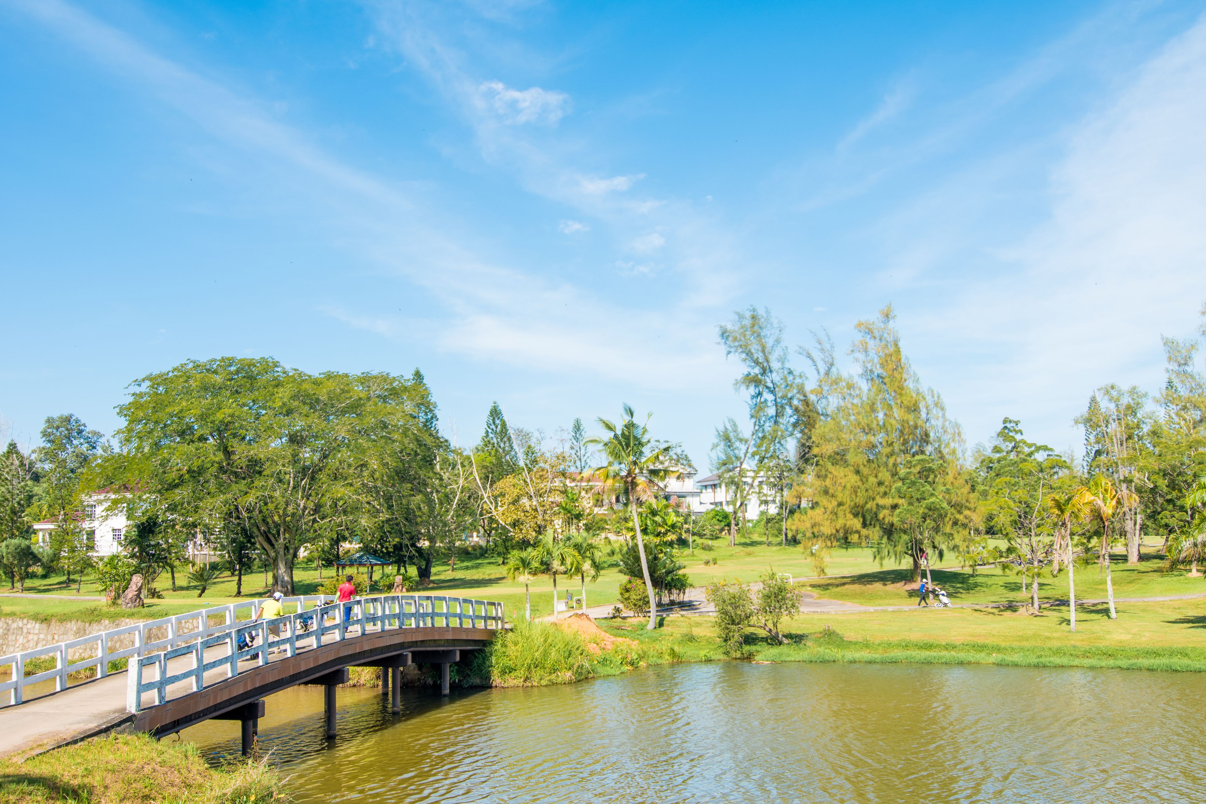A bridge over a calm body of water, surrounded by greenery and trees.