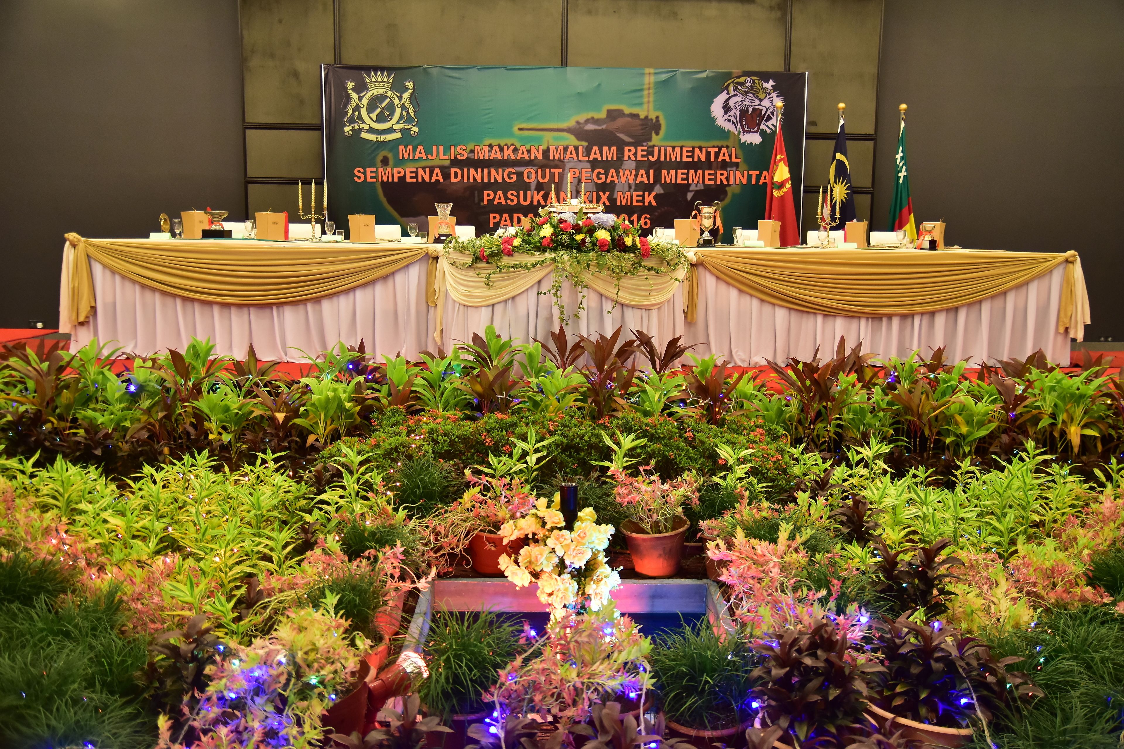 A decorated event table with a banner, trophies, and a floral arrangement.