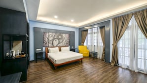 Una habitación de hotel moderna con piso de madera, una cama grande, un sillón amarillo, una mesita y un panel decorativo en la pared.