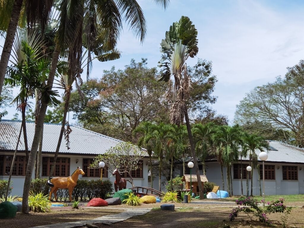Un patio con una estatua de caballo, palmeras y un edificio con tejado de baldosas.