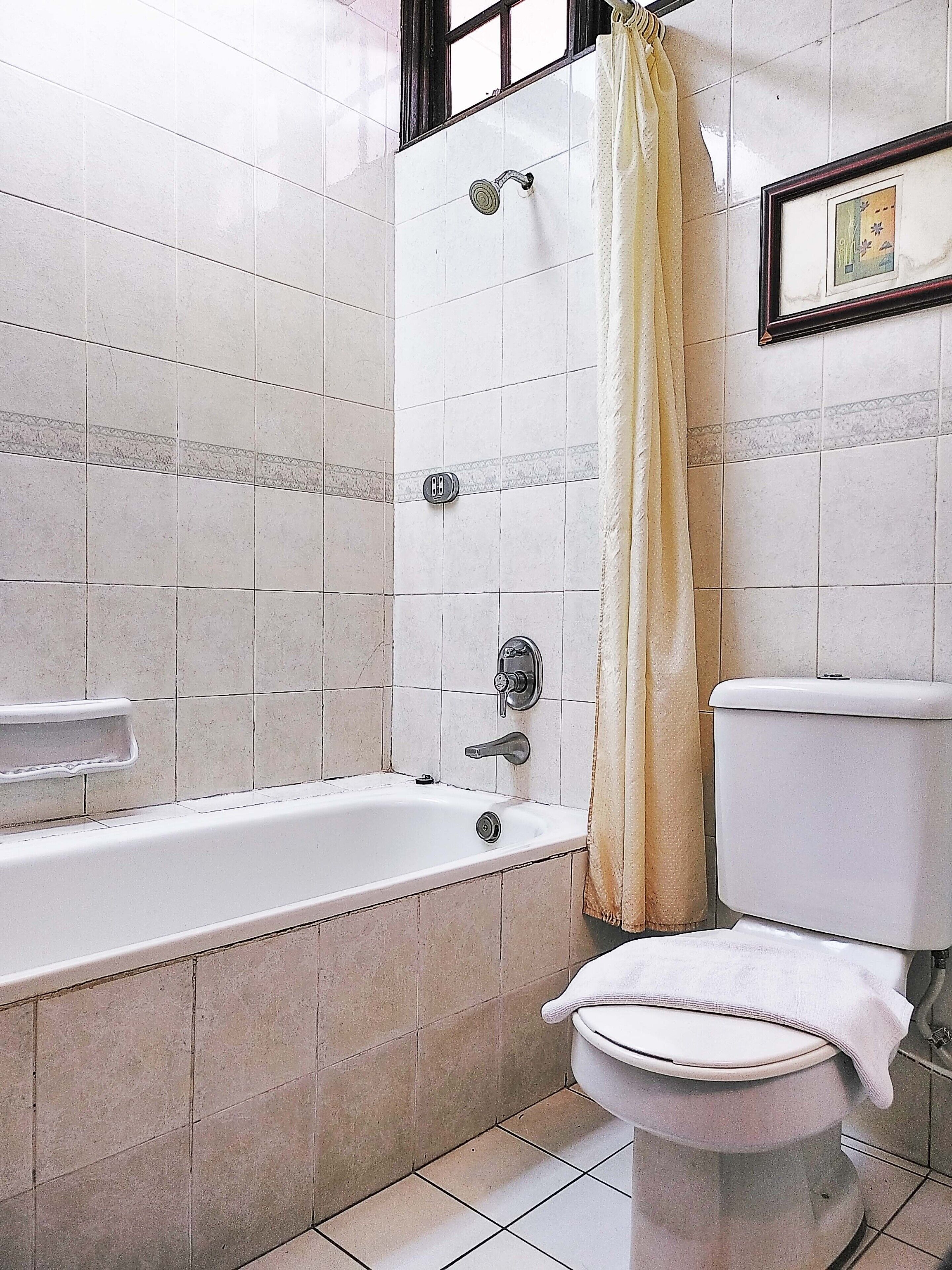 A bathroom with a bathtub, toilet, and shower curtain.