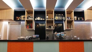 A kitchen with a black countertop, shelves with bottles, and a microwave. - Apo Hotel (Krabi)