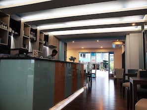 A modern kitchen with a glass partition, wooden cabinets, and a person cooking.