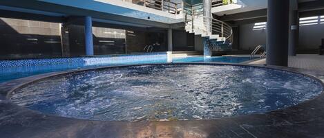 Zona de hidromasaje con piscina, escaleras y un paraguas amarillo.