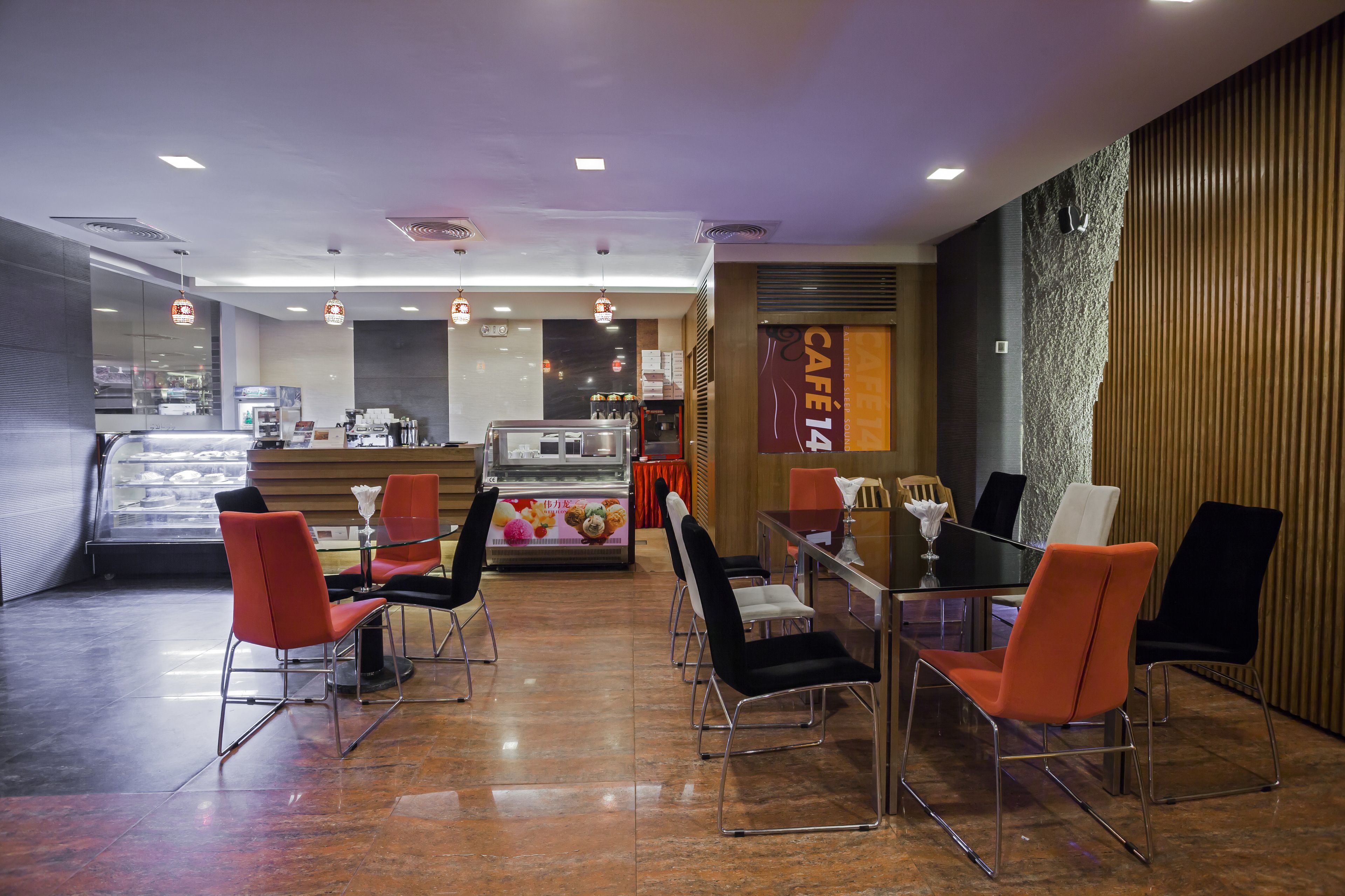 A modern cafe with a counter, seating area, and a dessert display.