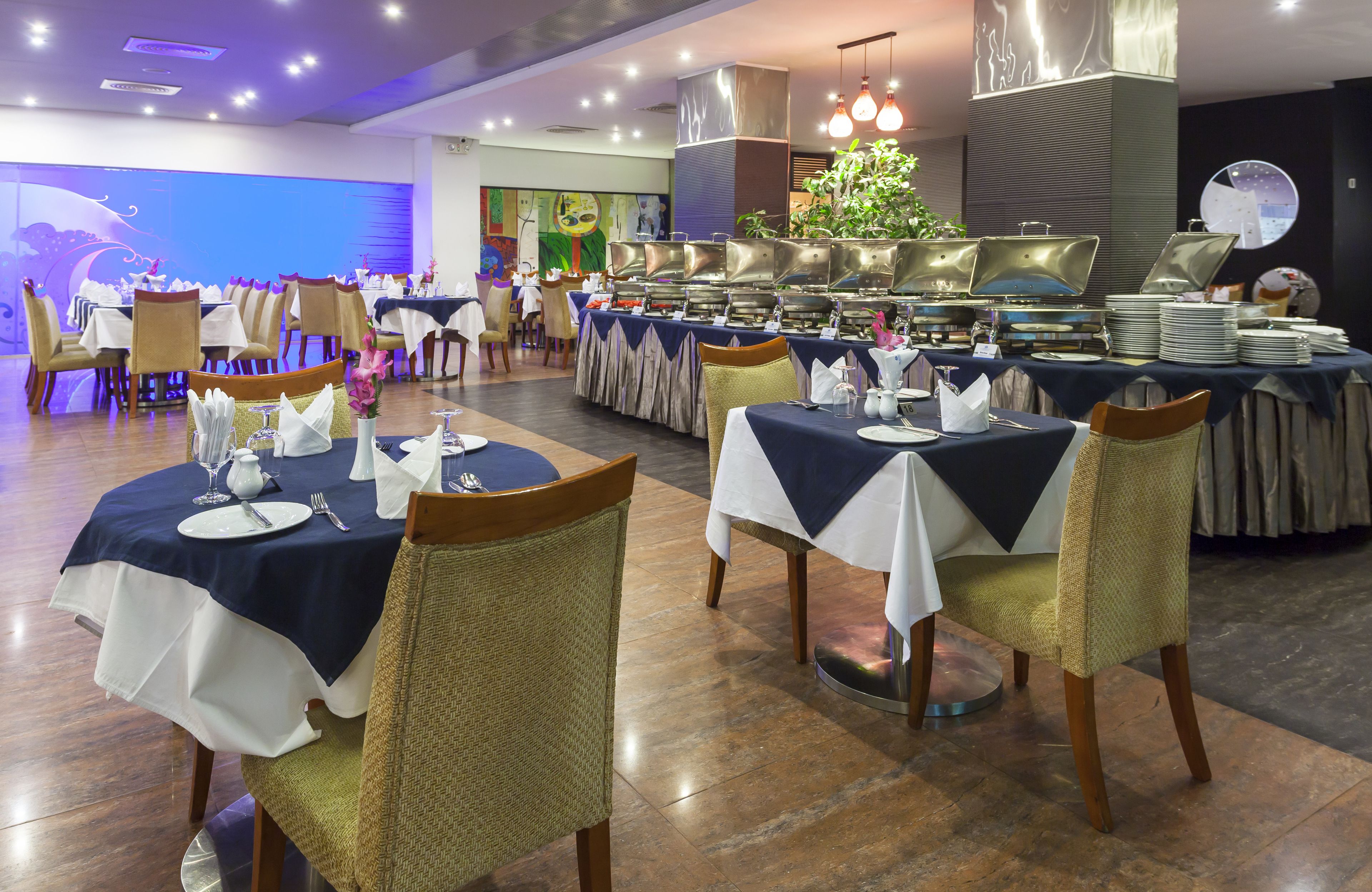 A restaurant with round tables, chairs, and a buffet area.