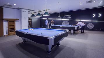 A pool table in a room with modern lighting fixtures and a black wall with directional arrows.