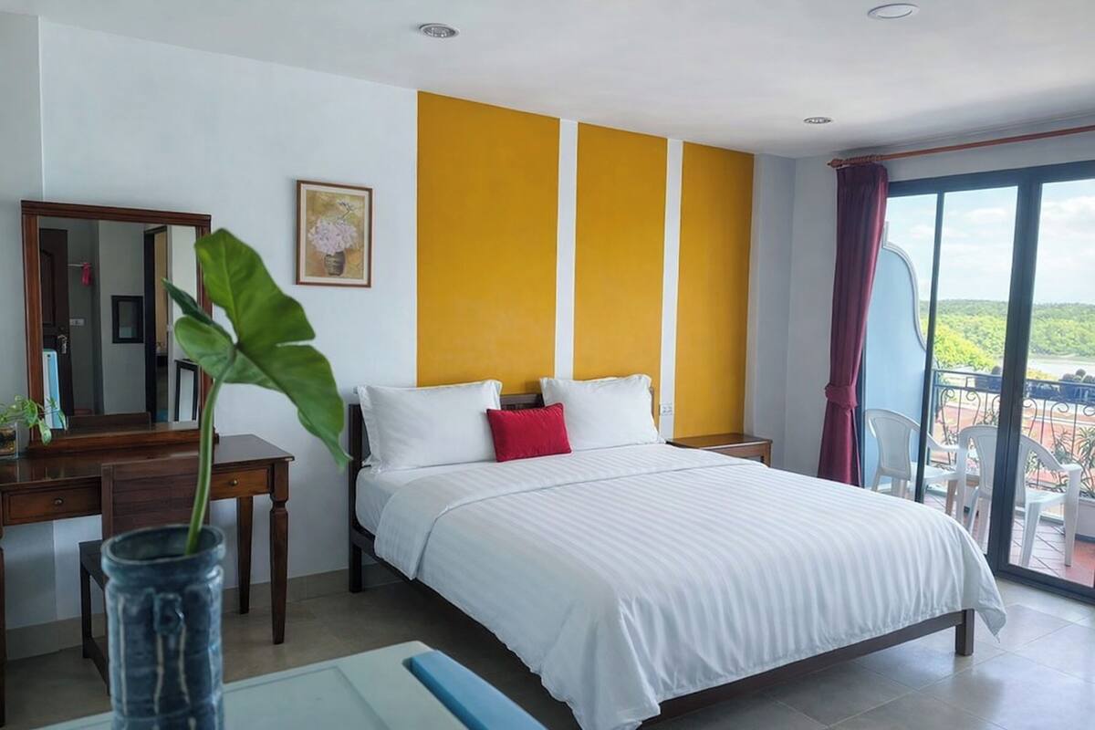 Een hotelkamer met een bed, een bureau, een stoel, een groot raam en een balkon.