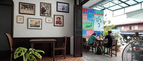 Un restaurante con piso de baldosas, cuadros en la pared y un ventilador grande.