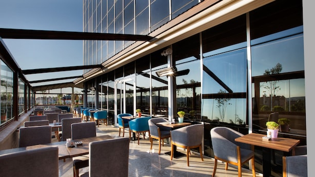 A modern outdoor seating area with glass walls, providing views of the cityscape.
