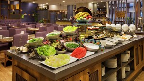 A buffet with various food items and a seating area with purple chairs.