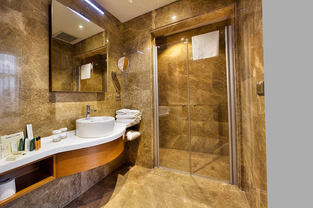 A modern bathroom with a marble vanity, a glass shower enclosure, and a large mirror.