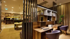 A modern office space with a wooden desk, two purple chairs, a computer, and a bookshelf.