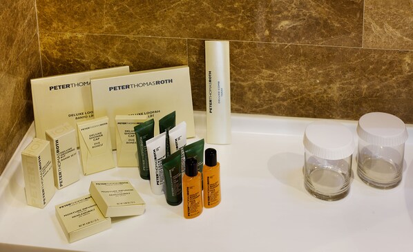 Una encimera de baño con varios productos para el cuidado de la piel Peter Thomas Roth, incluyendo cajas, tubos y botellas.