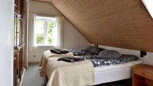 Camera da letto con due letti, soffitto in legno e una finestra con tende.