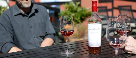 A table with a bottle of Alamos Malbec 2018 wine, two glasses of red wine, and a person seated in the background.