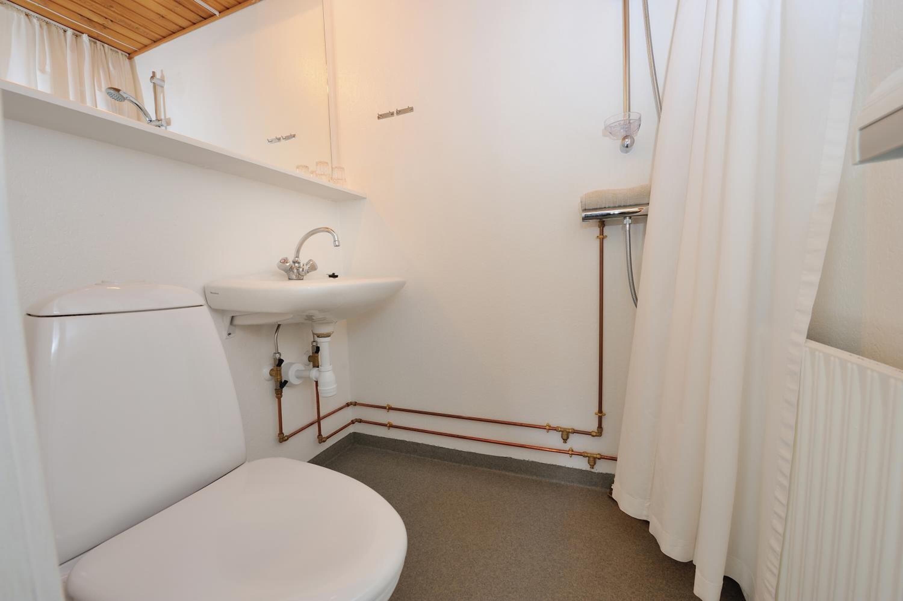 A small, clean bathroom with a toilet, sink, and shower.