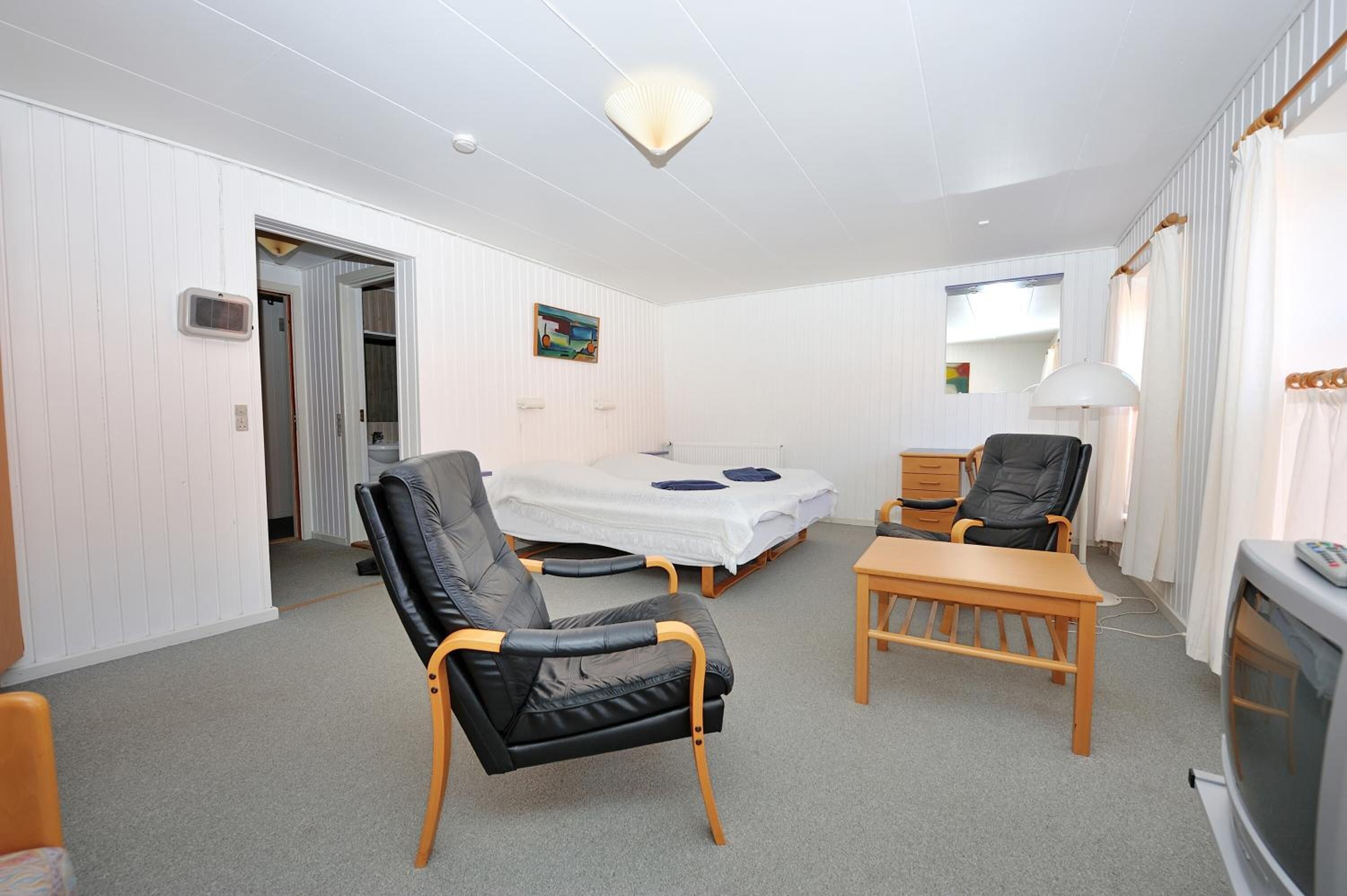 A compact room with a bed, a desk, a chair, and a television.