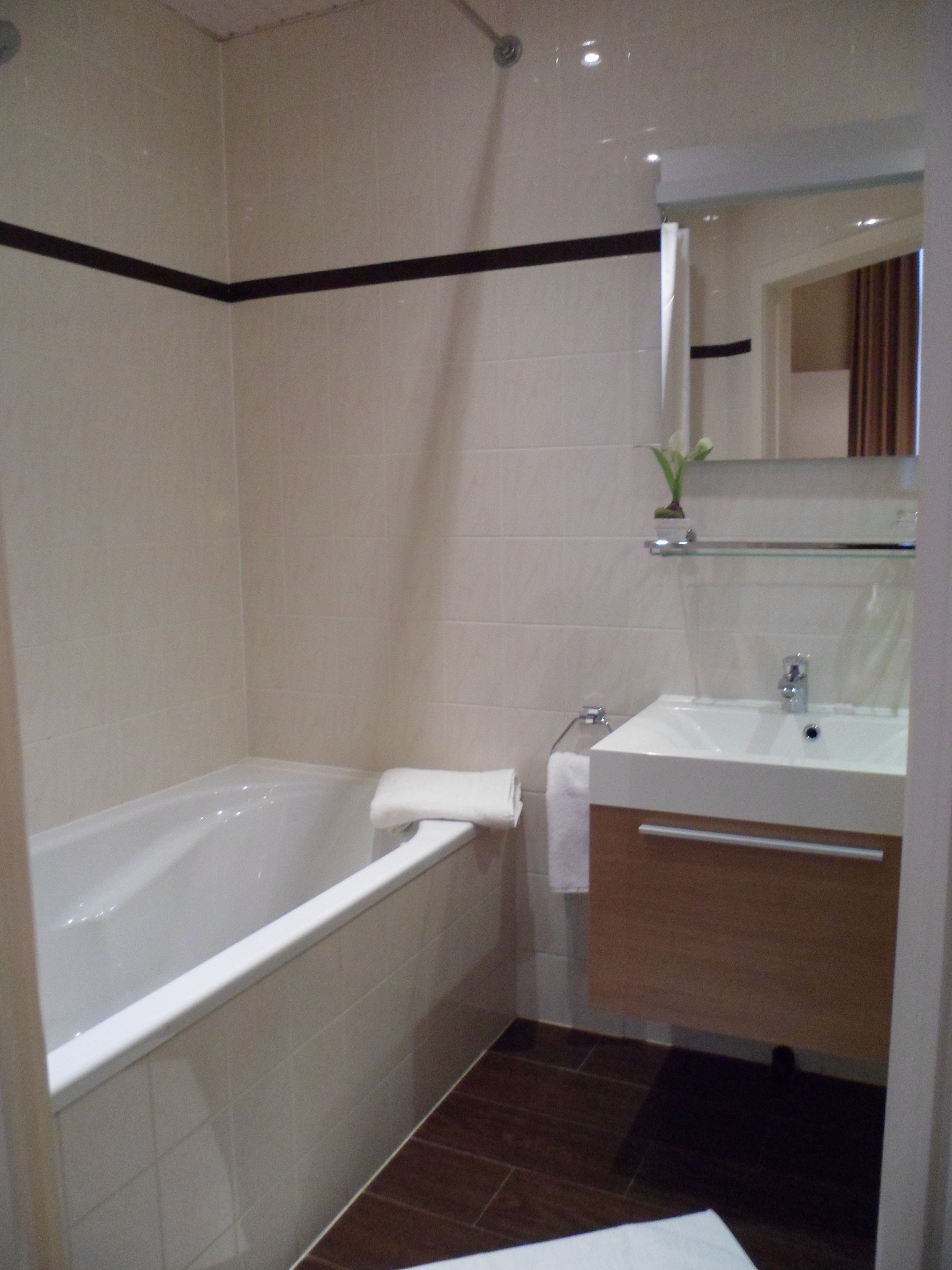 A bathroom with a bathtub, a sink, and a mirror.