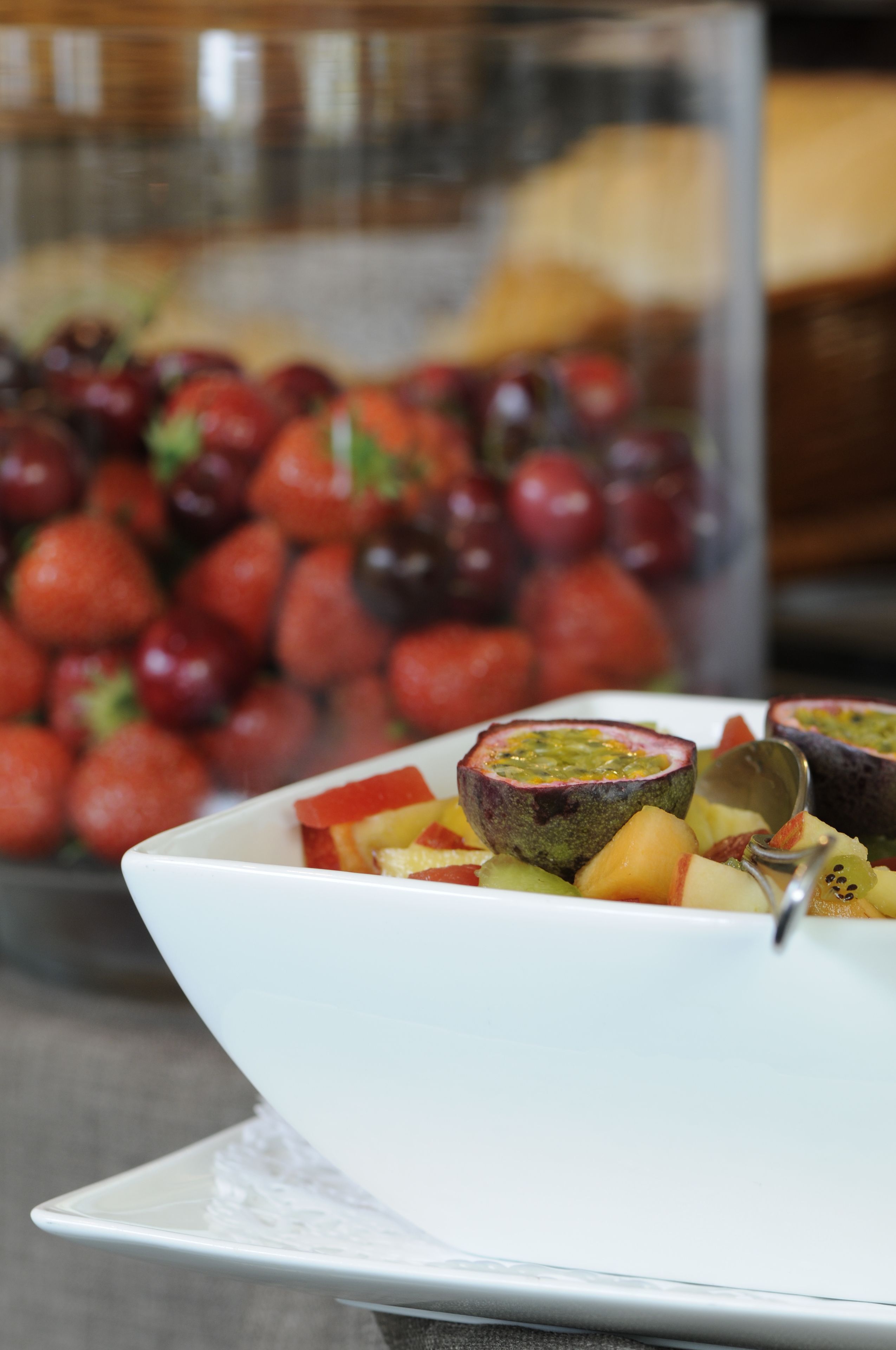 Un bol blanc rempli d’un assortiment de fruits, posé sur une table.