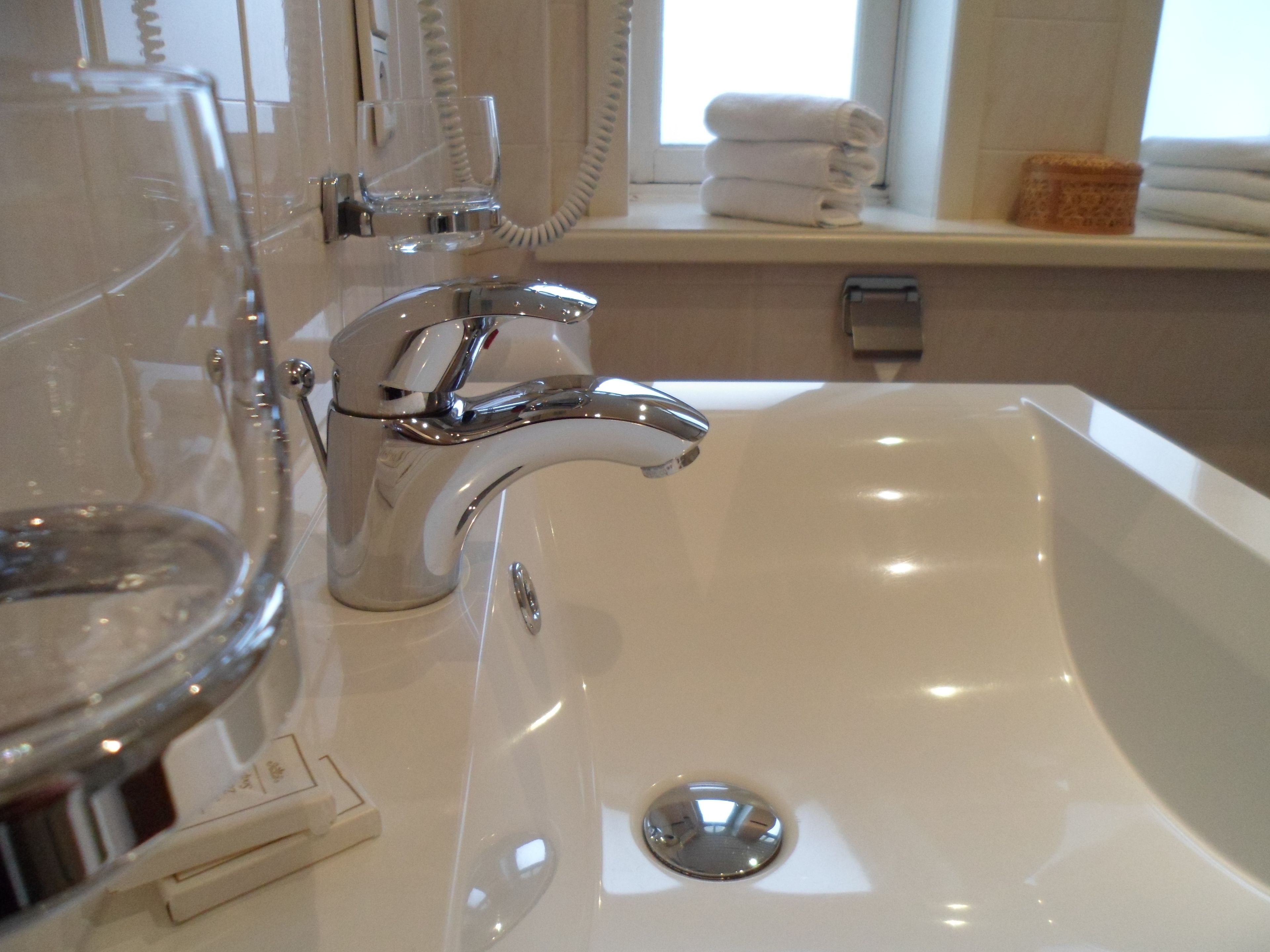Un baño moderno con grifo cromado, cabina de ducha con mampara de vidrio y lavabo blanco.