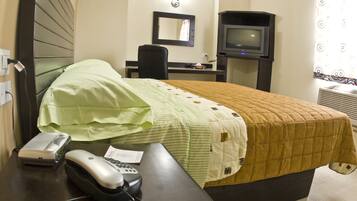 A hotel room with a bed, a desk with a telephone and a speaker, a chair, a television, and a window with a curtain.
