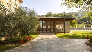 A pathway leading to a building with large glass windows and a covered area. - Catignano Hotel (Gubbio)