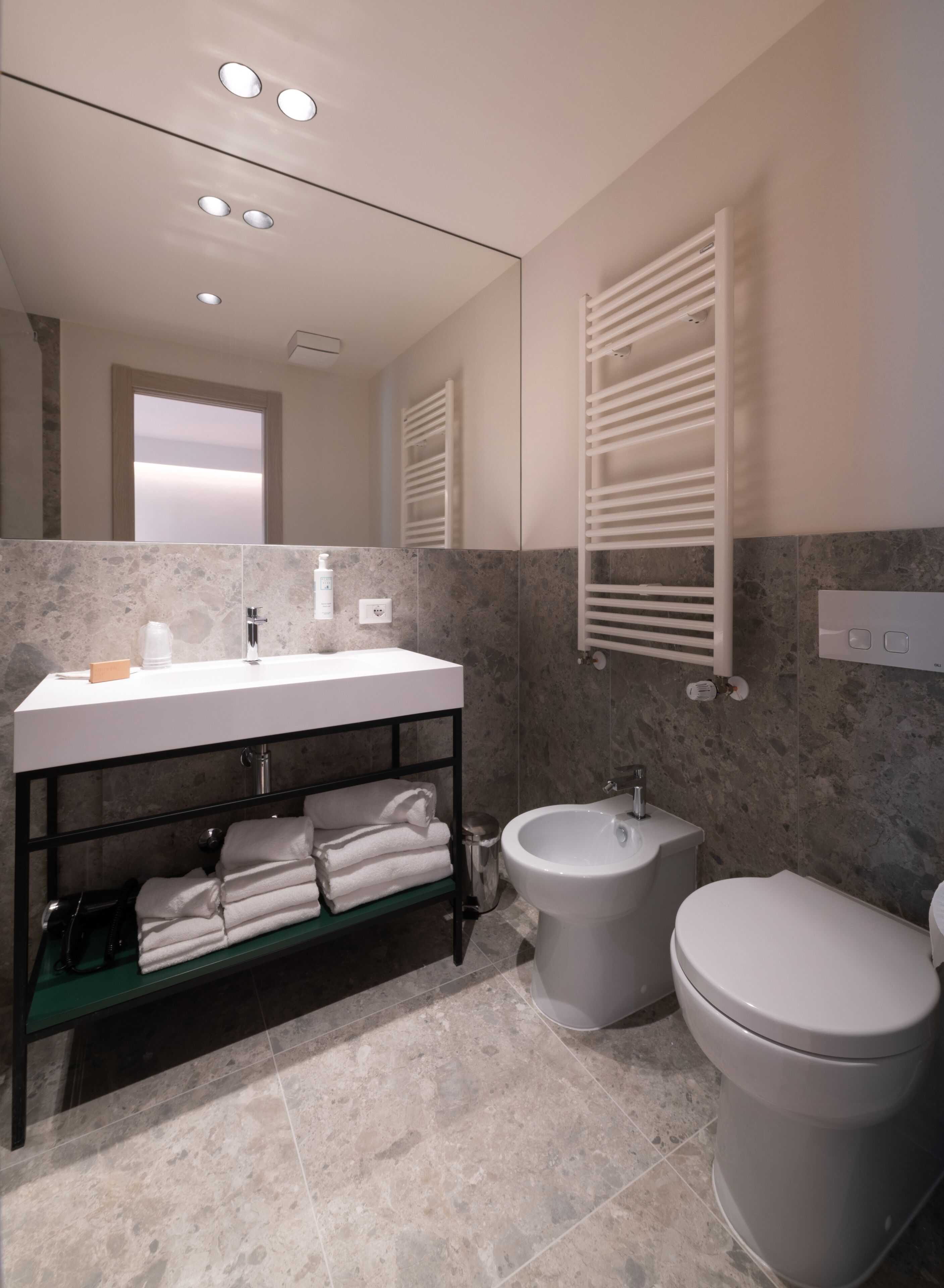 A modern bathroom with a large mirror, a vanity with a sink, a bidet, and a toilet.