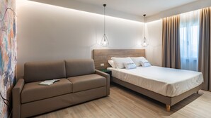 Ein modernes Hotelzimmer mit einem Bett, einer Couch und einem Nachttisch.