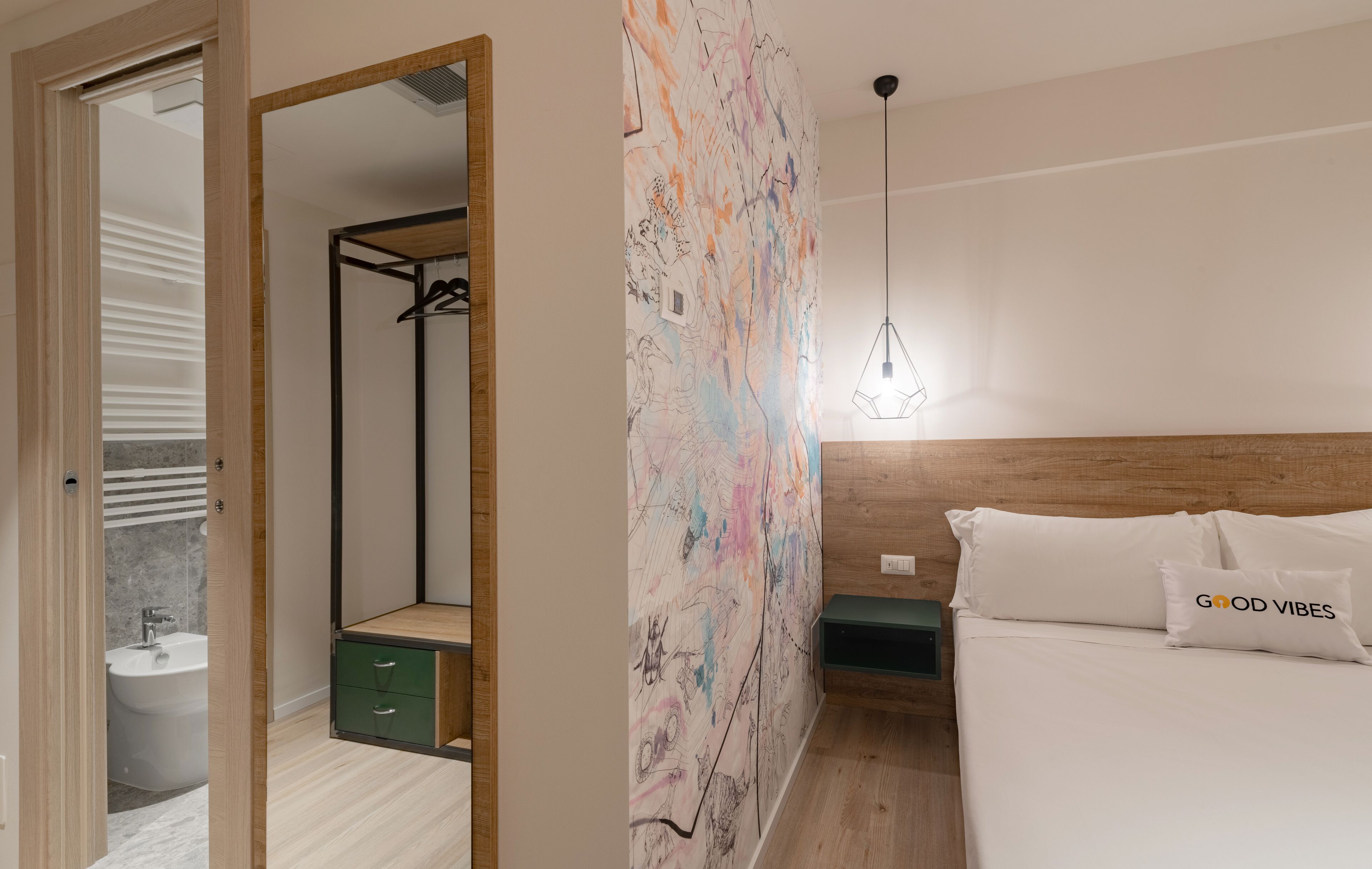 A modern bedroom with a wooden headboard, a large abstract mural, and a hanging light fixture.