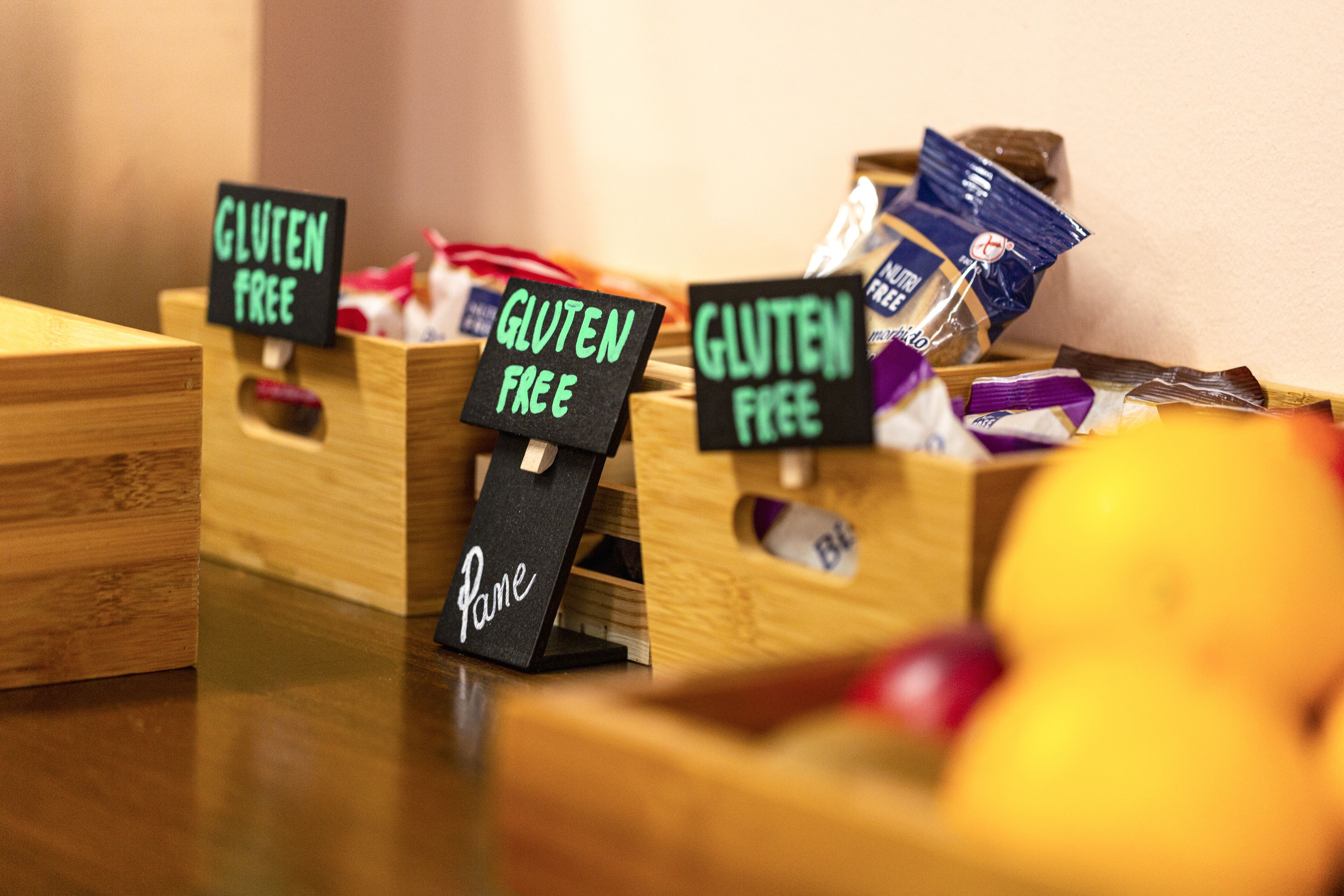 Holzkisten mit verschiedenen verpackten Artikeln, gekennzeichnet als glutenfrei.